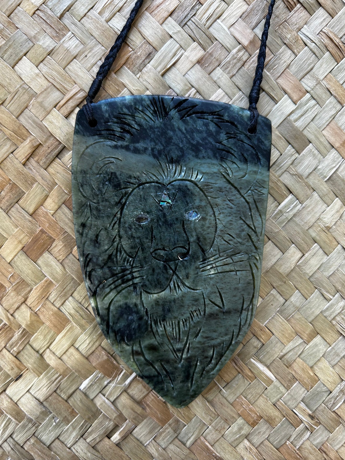 intricately carved pounamu necklace, paua inlay, taniko and raiona (lion) design, on black cord, limited edition, large