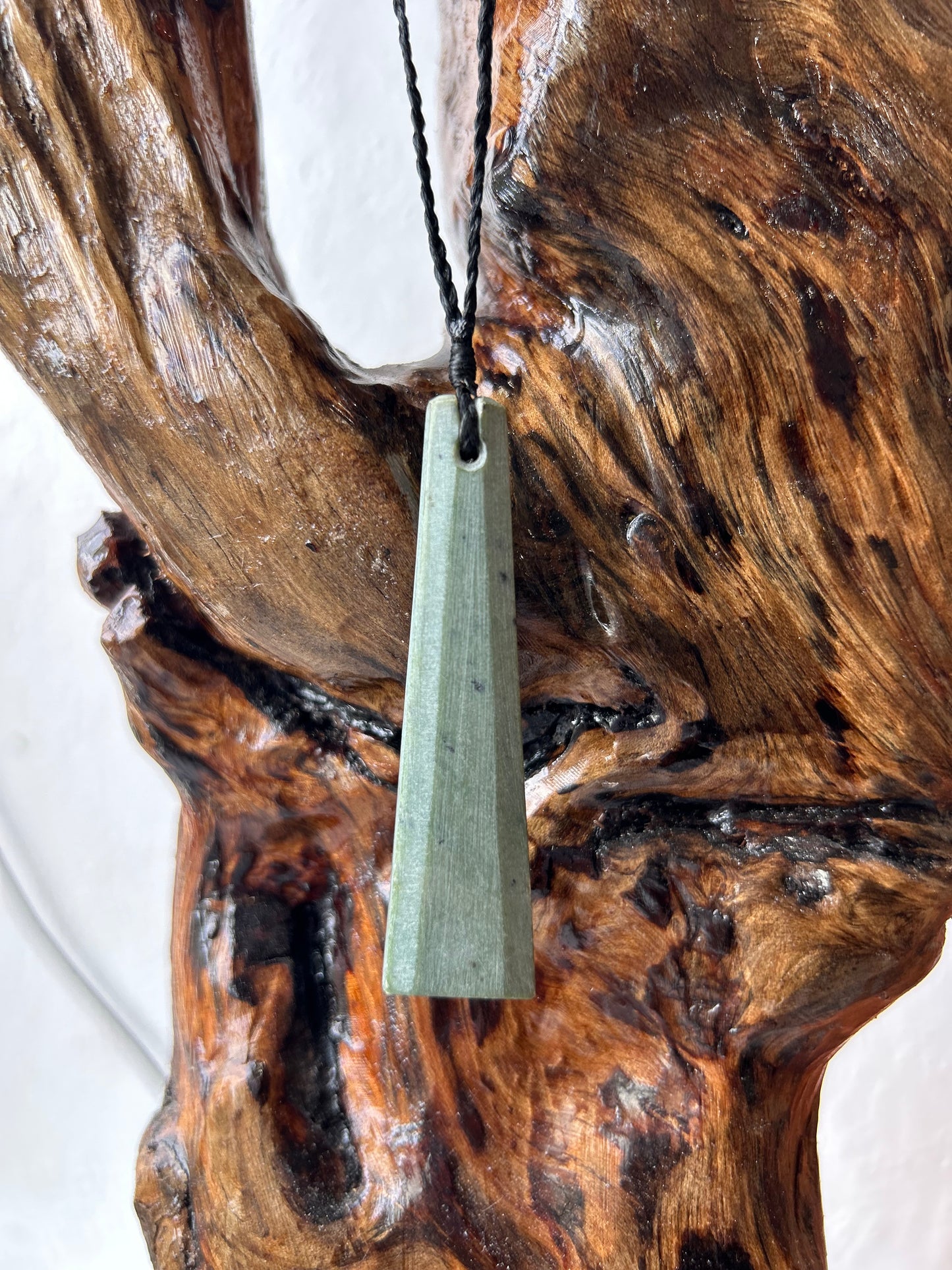 carved pounamu toki (adze) necklace with bevelled edges, on black cord