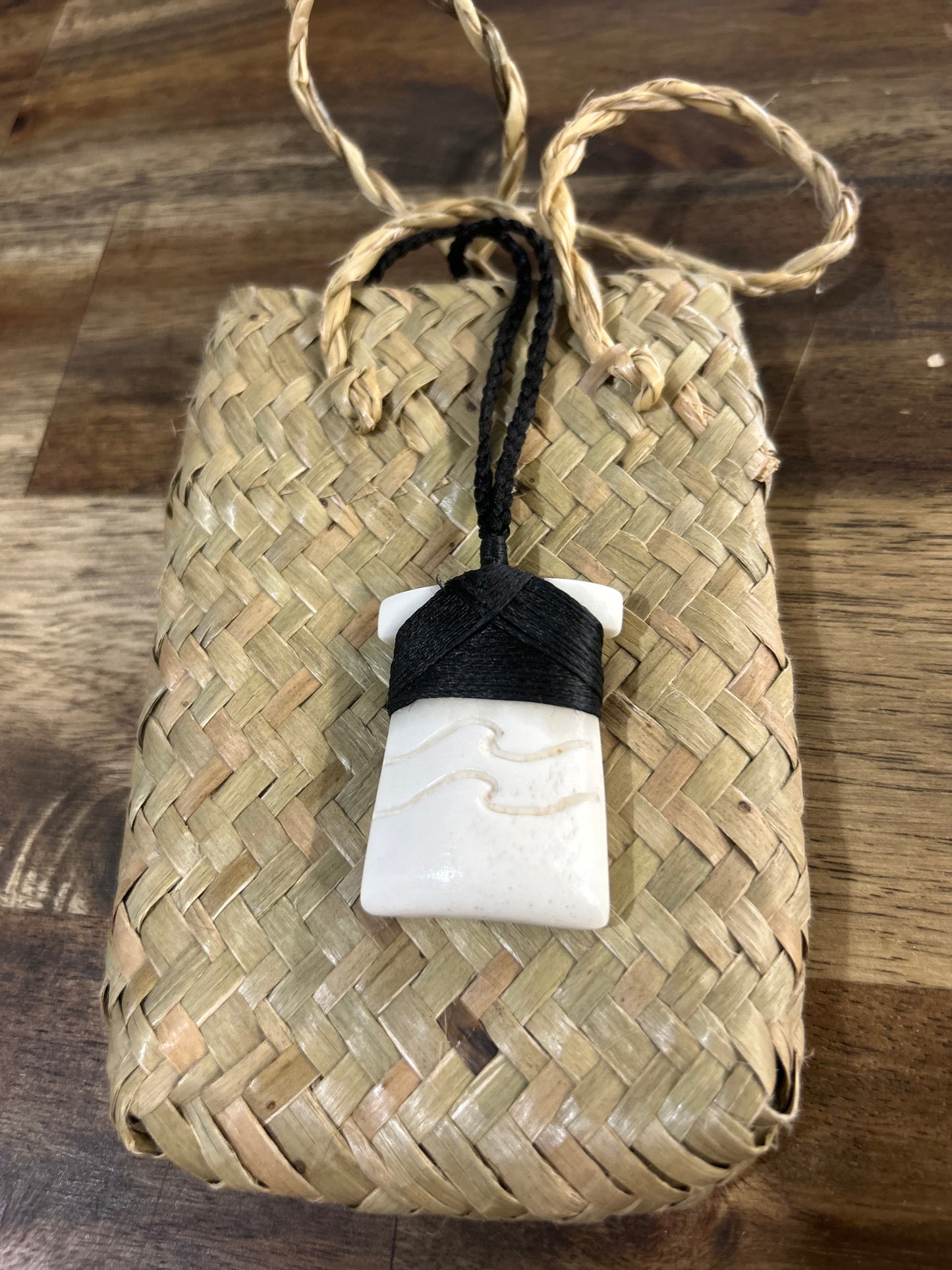 carved bone toki (adze) necklace with carved ngaru (wave) designs on black lashing