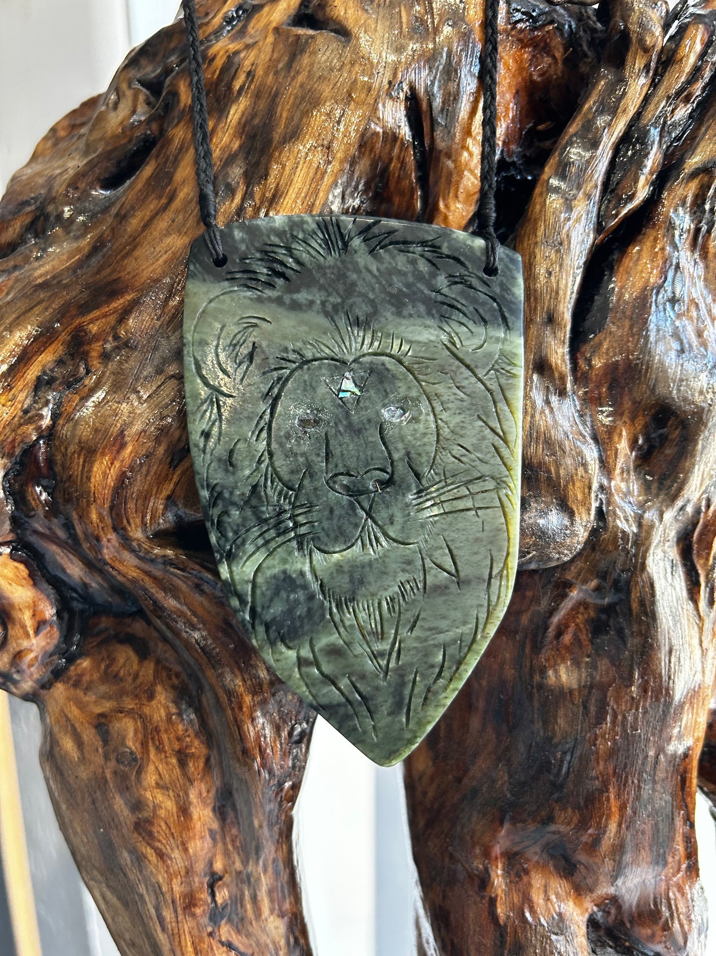 intricately carved pounamu necklace, paua inlay, taniko and raiona (lion) design, on black cord, limited edition, large