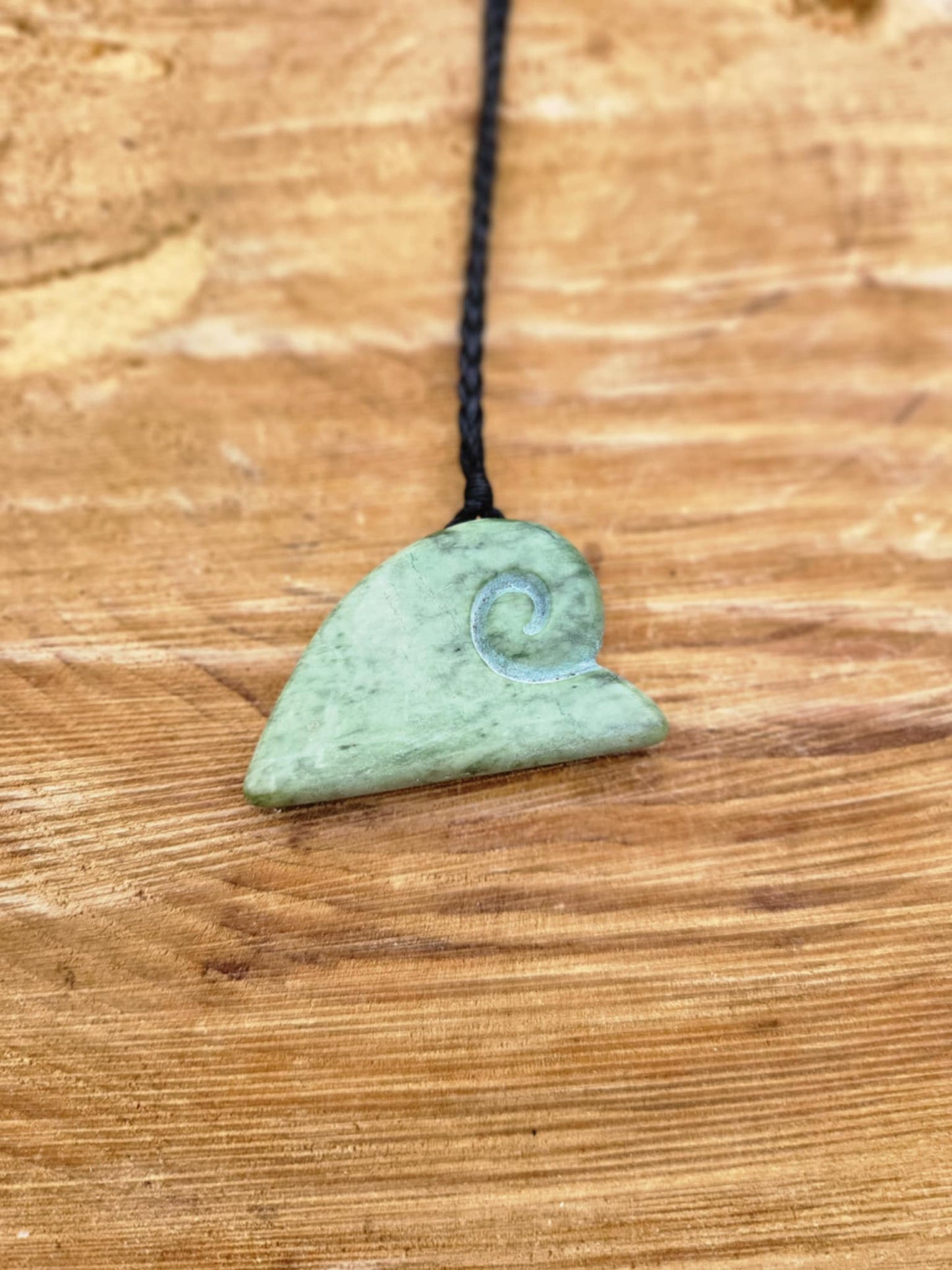 ngaru (wave) carved pounamu necklace on black cord
