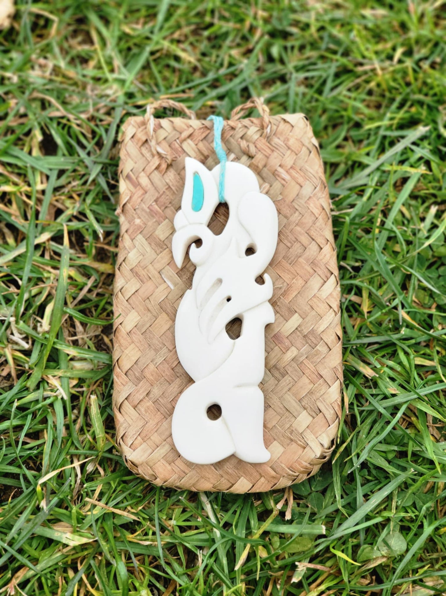intricately carved bone manaia necklace on blue cord