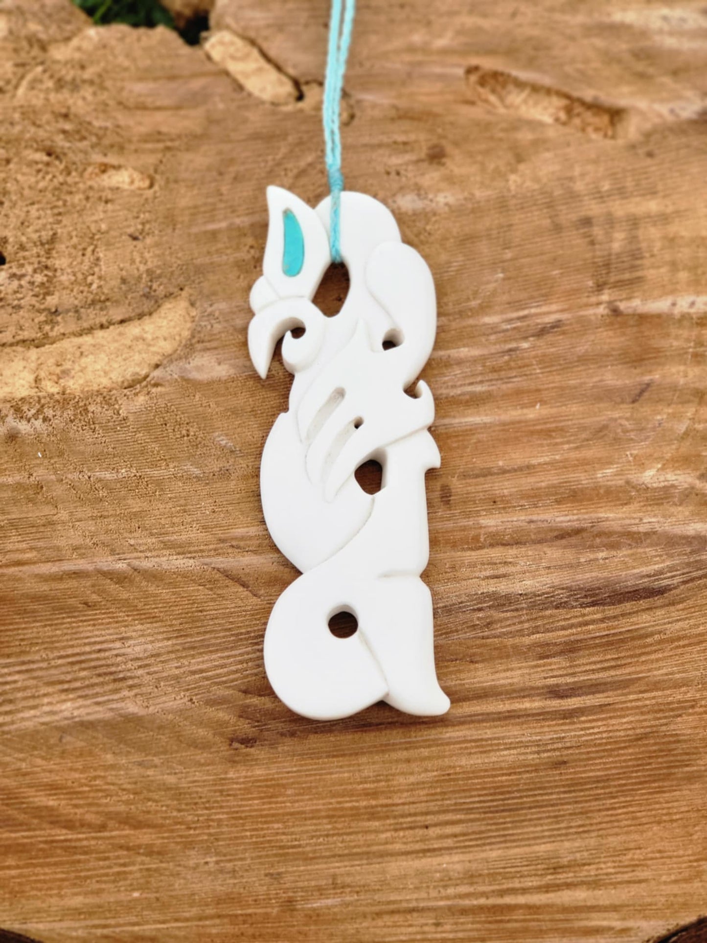 intricately carved bone manaia necklace on blue cord