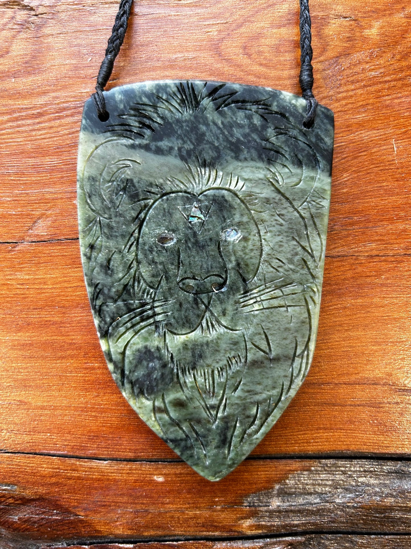 intricately carved pounamu necklace, paua inlay, taniko and raiona (lion) design, on black cord, limited edition, large