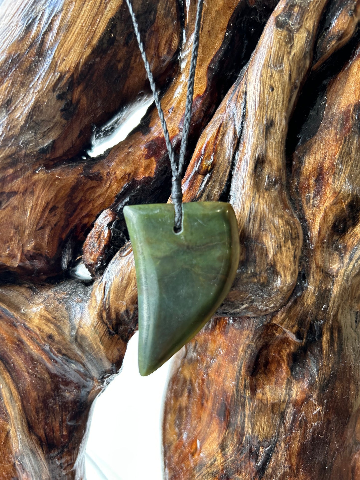 Carved pounamu niho (tooth) necklace on black cord