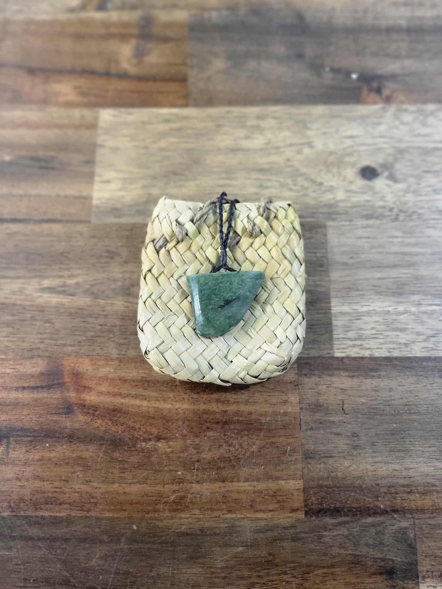 Carved pounamu (greenstone) niho (tooth) necklace on black braiding