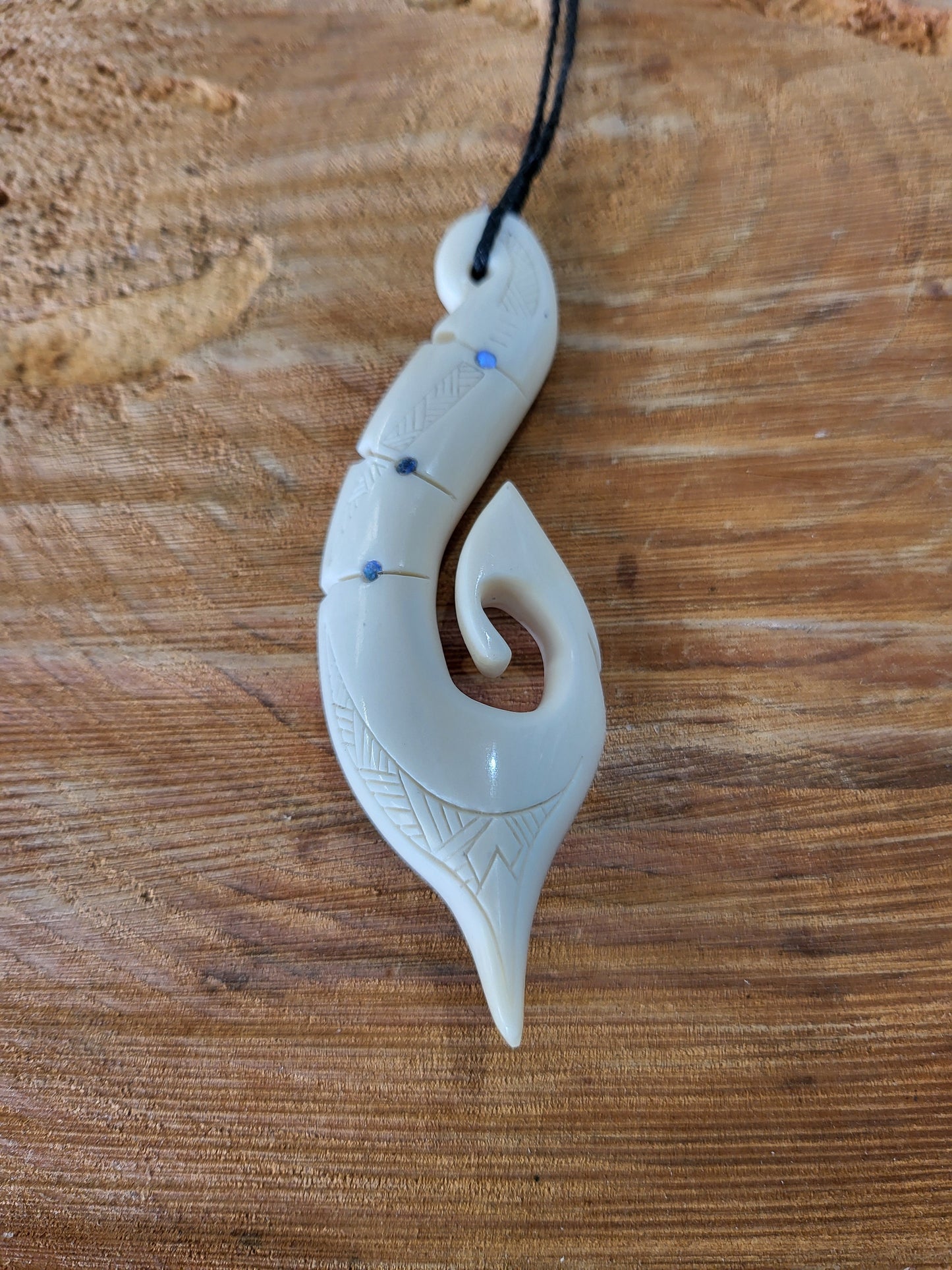 carved bone and paua matau (hook) necklace on black cord, with carved patterns