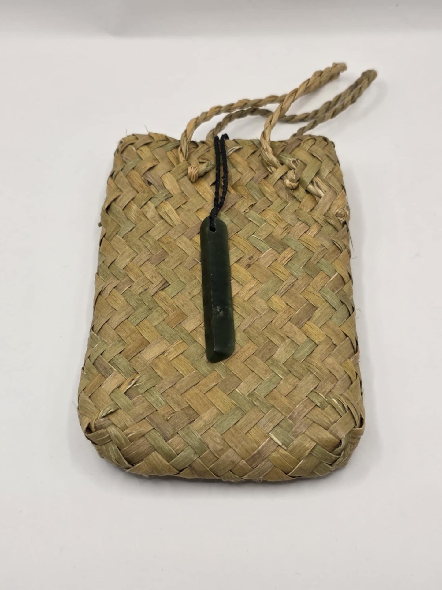 small carved pounamu toki (adze) necklace, with black lashing