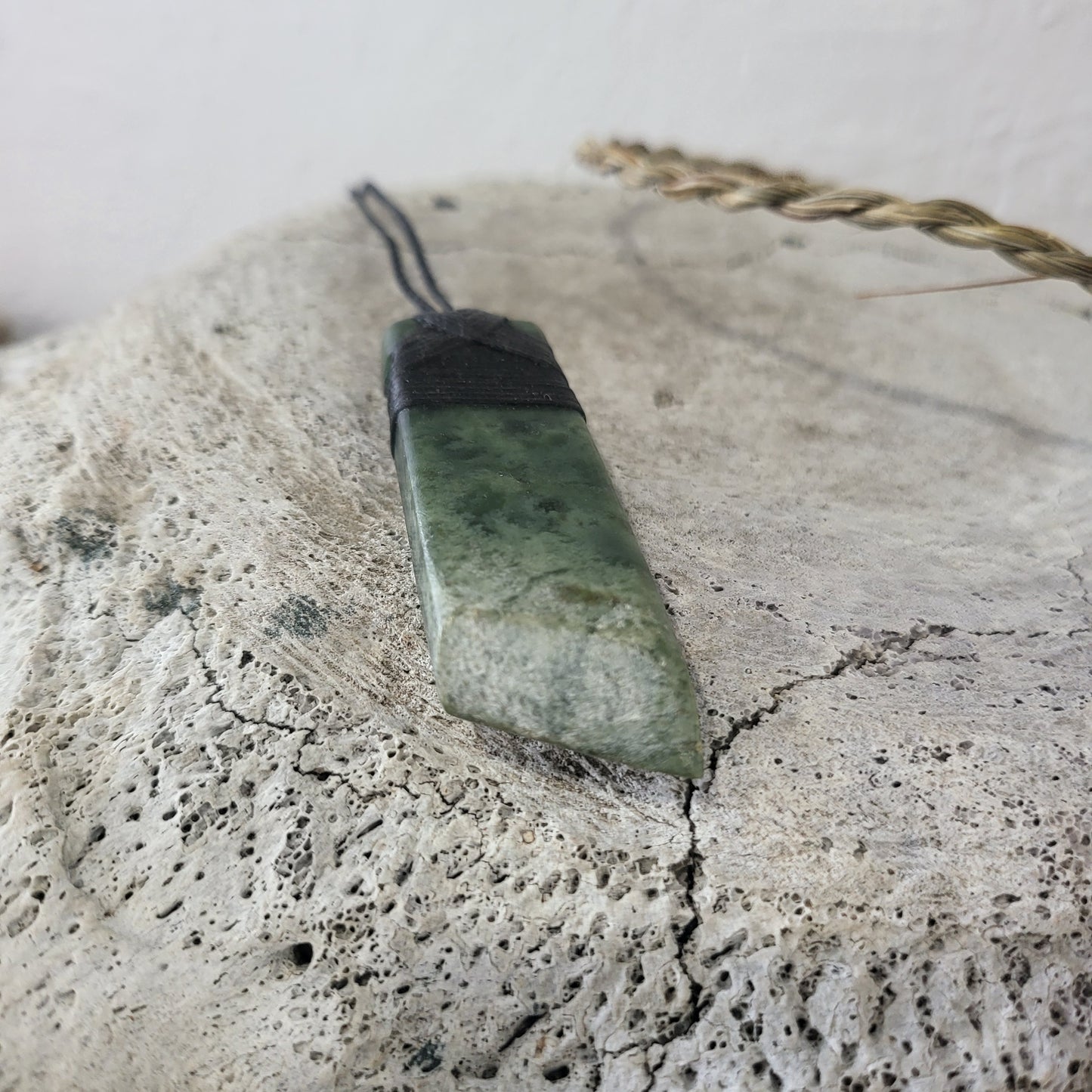 carved pounamu toki (adze) necklace, beautiful colour variations, asymmetrical base, on black cord