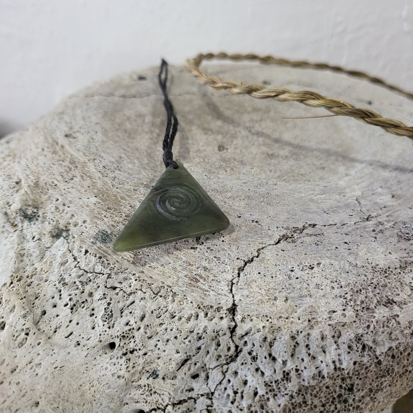 carved pounamu tapa toru (triangle) necklace, on black cord, with carved puhoro design