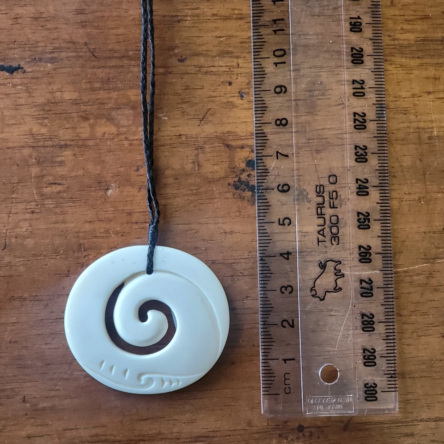 carved bone koru (spiral) necklace on black cord with carved designs