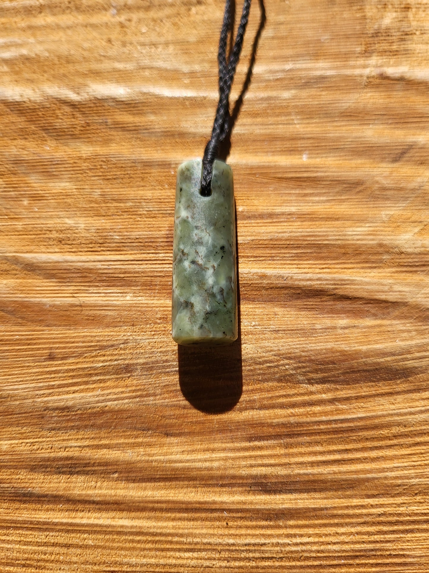 small carved pounamu toki (adze) necklace on black cord
