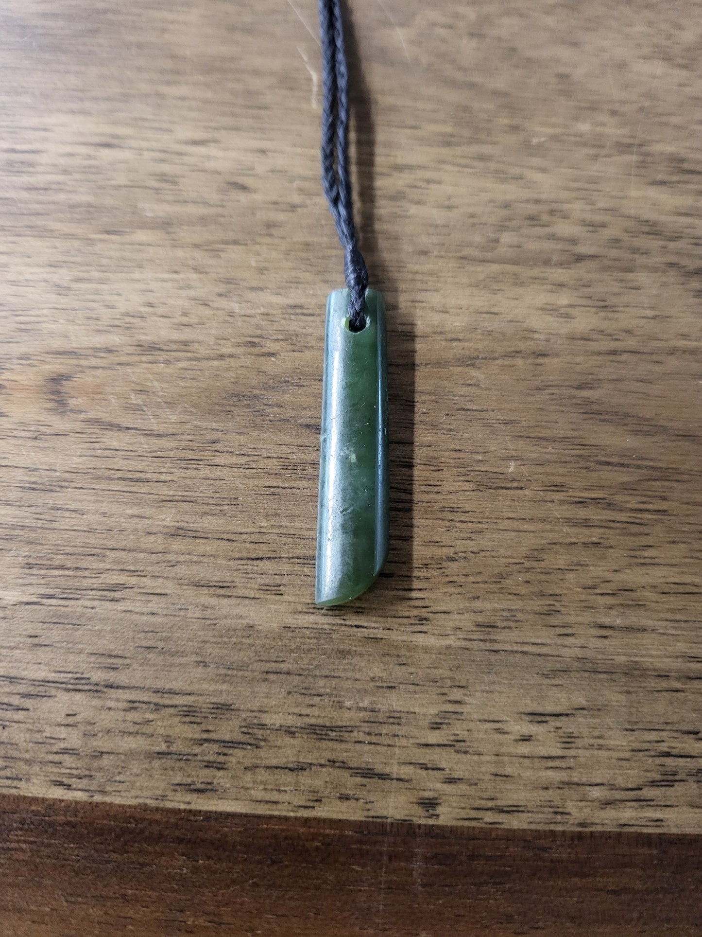 small carved pounamu toki (adze) necklace, on black cord