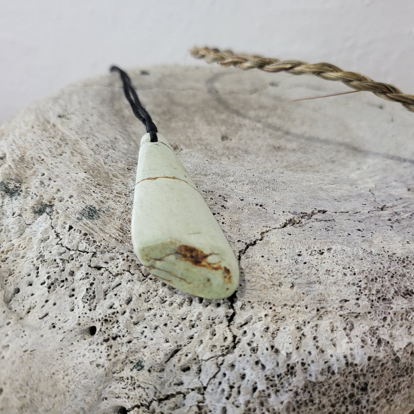 very light green carved pounamu roimata (tear drop) necklace, on black cord