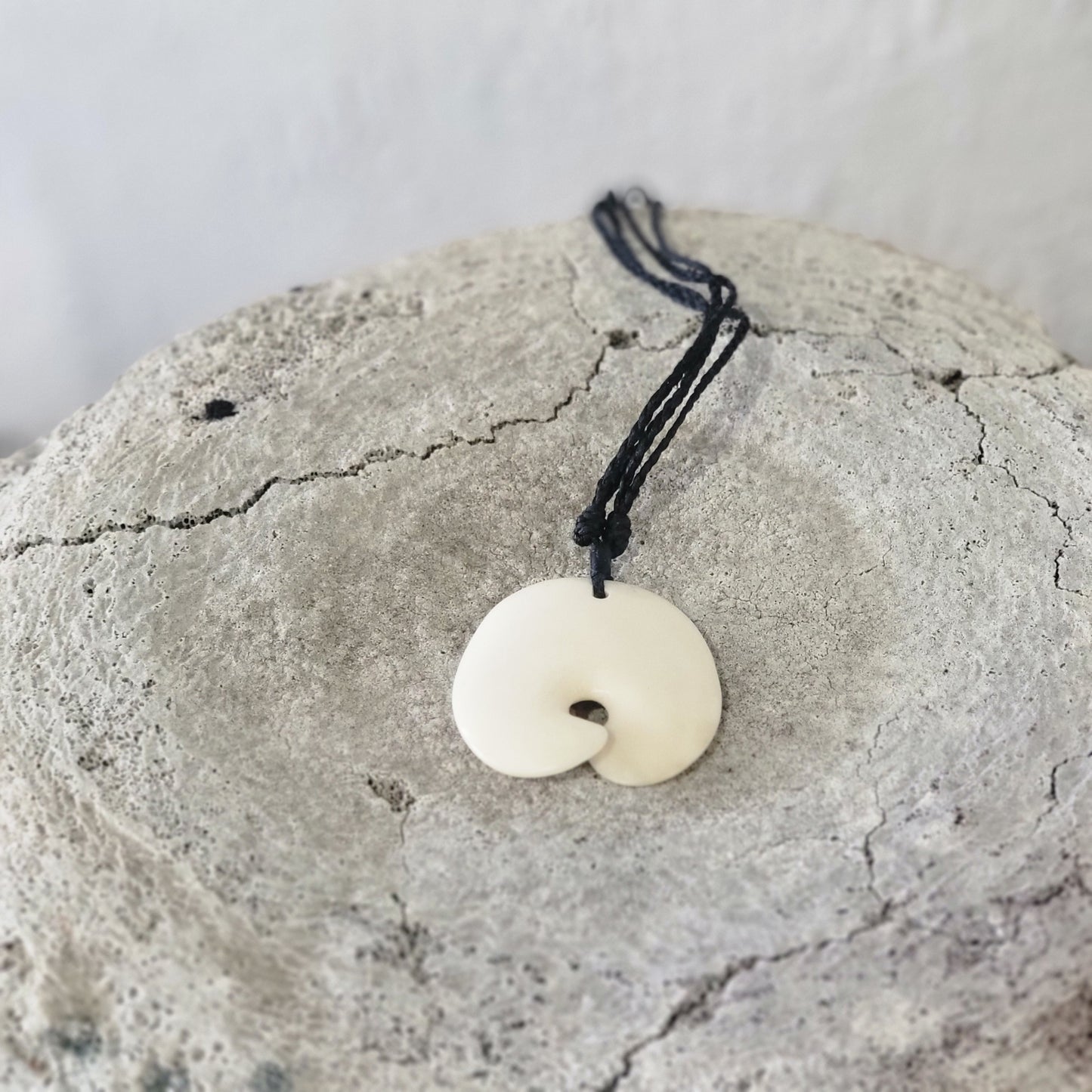carved bone tohora (whale) tail necklace on black cord with carved designs