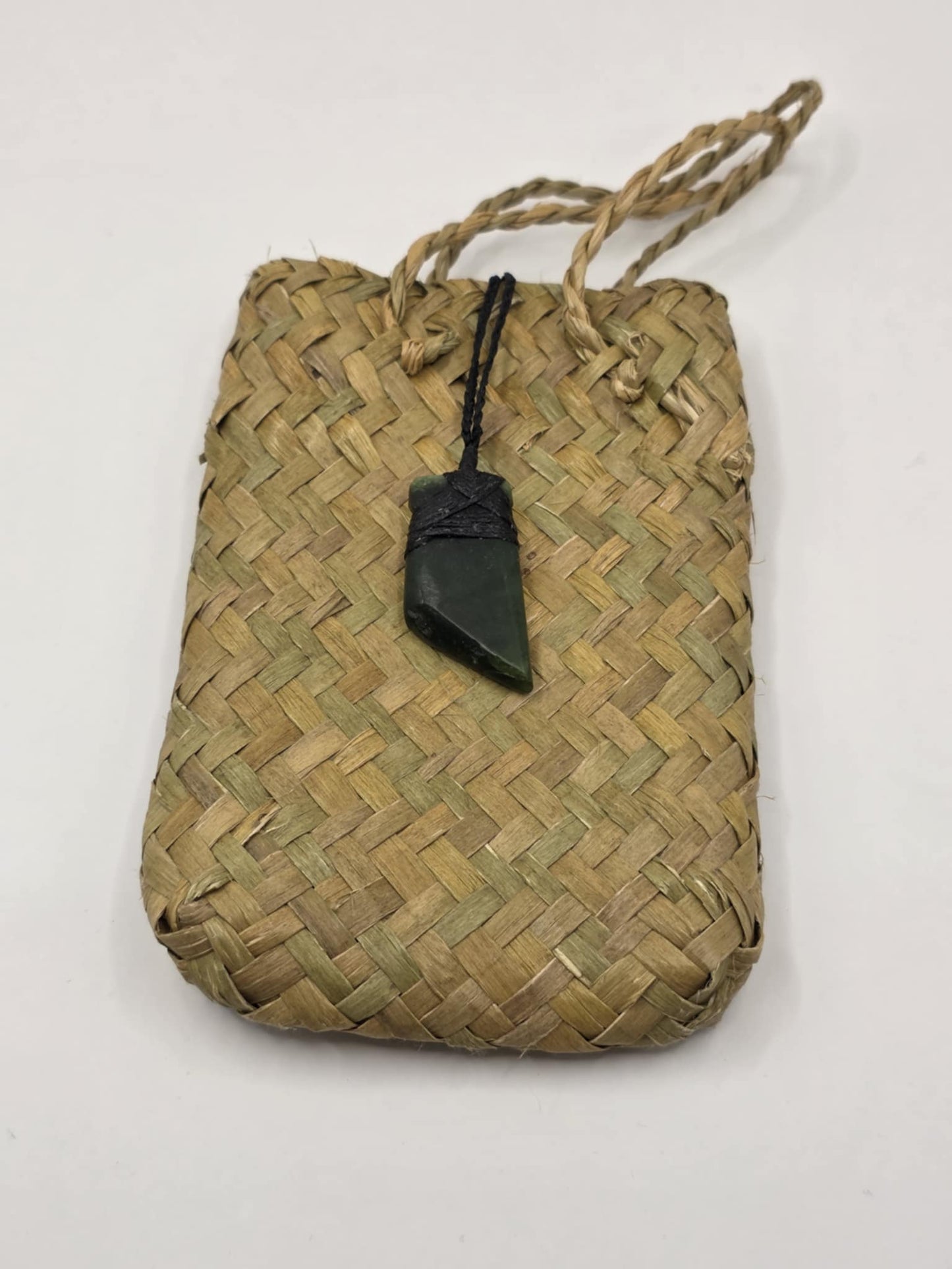 small carved pounamu toki (adze) necklace, with black lashing