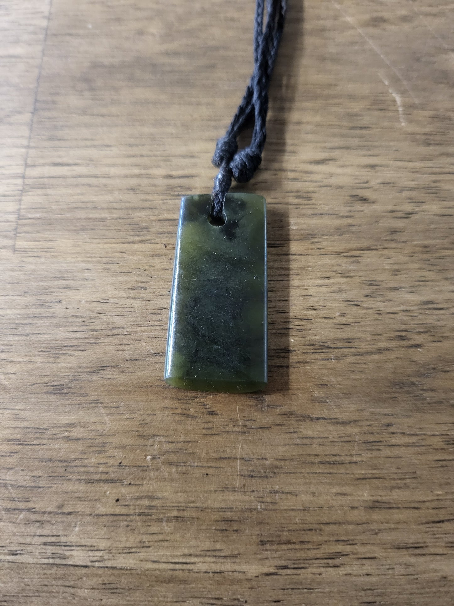 small carved pounamu toki (adze) necklace, on black cord