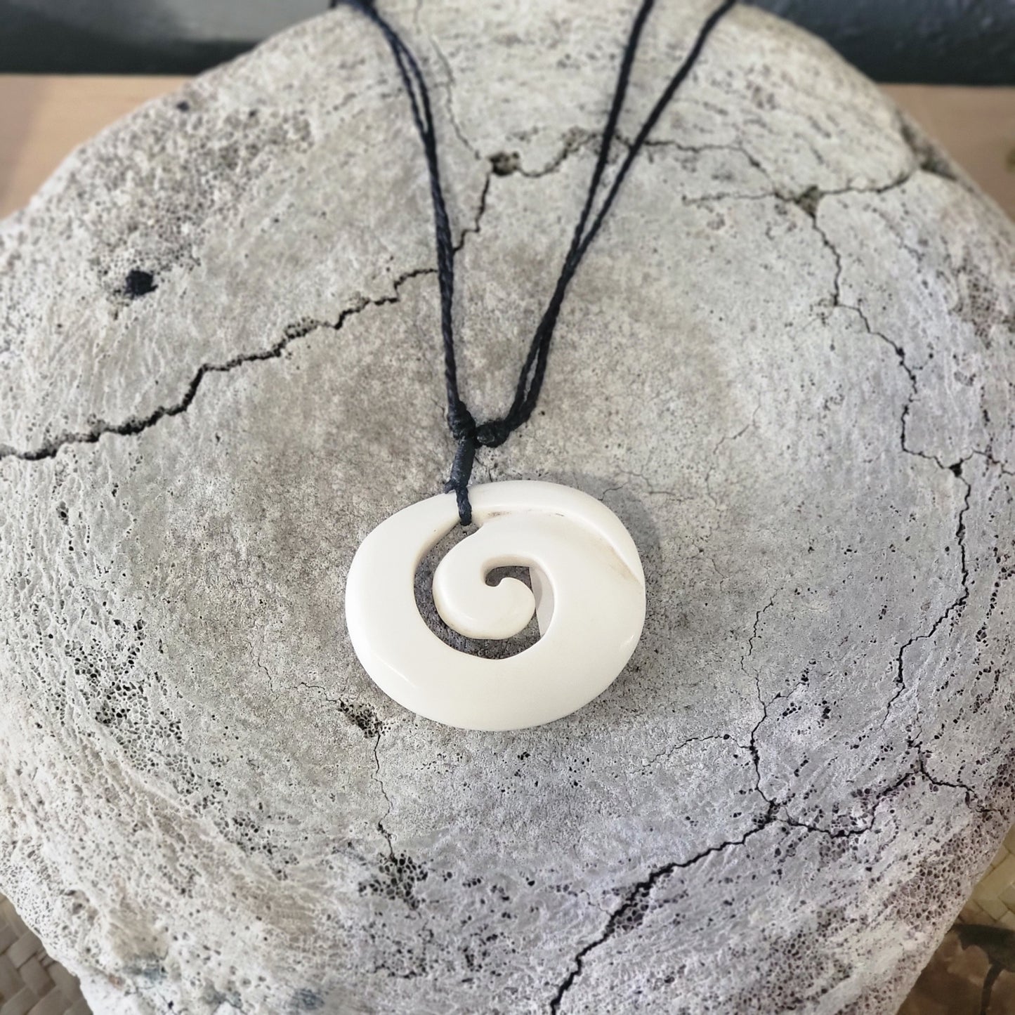 carved bone koru (spiral) necklace on black cord with carved designs