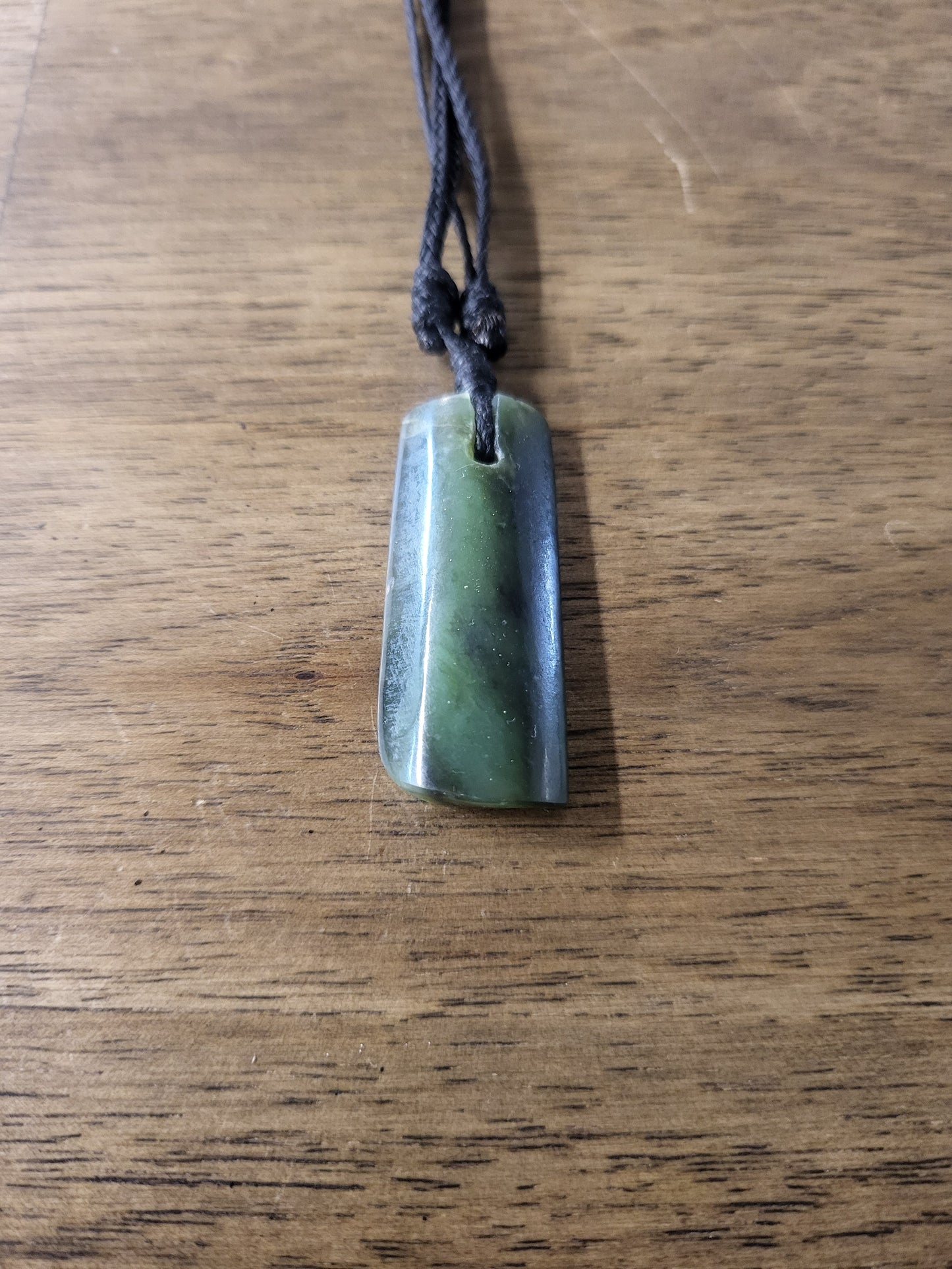 small carved pounamu toki (adze) necklace, on black cord