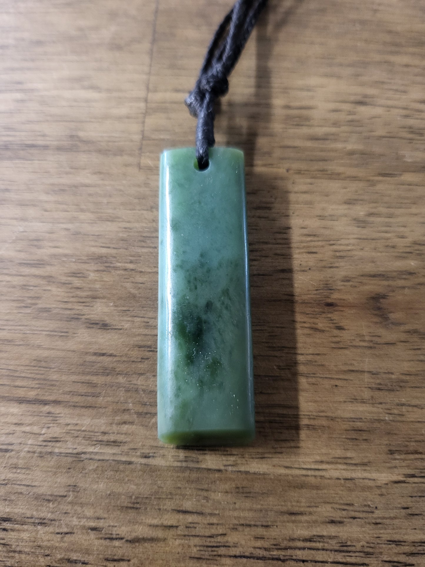 small carved pounamu toki (adze) necklace, on black cord