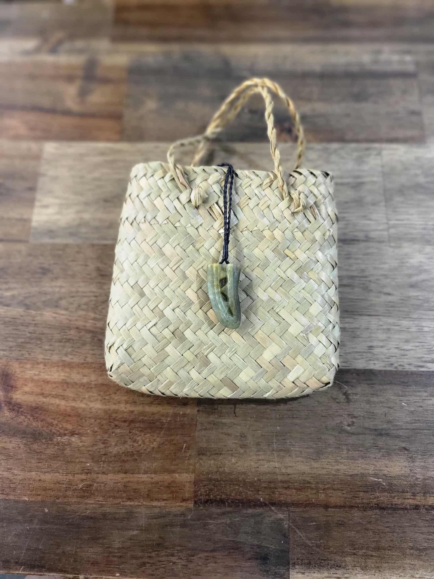 Light green pounamu (greenstone) niho (tooth) necklace on black braiding, carved with niho designs