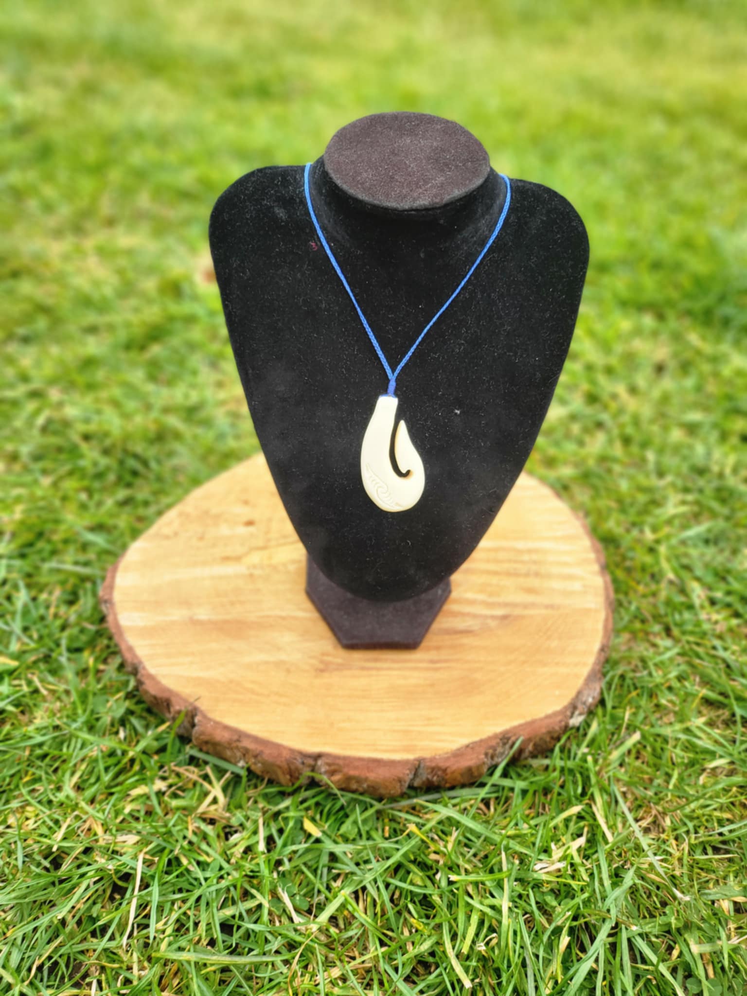 carved bone matau (hook) necklace with koru carvings on black cord
