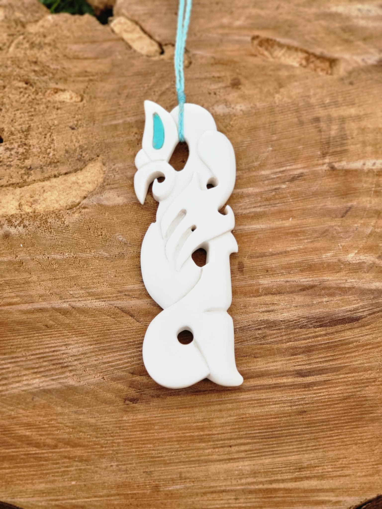 intricately carved bone manaia necklace on blue cord
