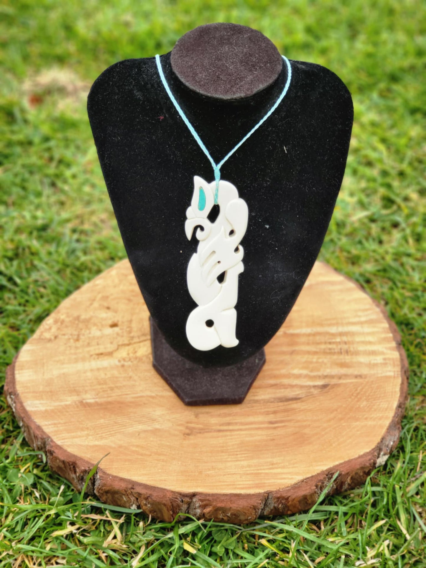 intricately carved bone manaia necklace on blue cord