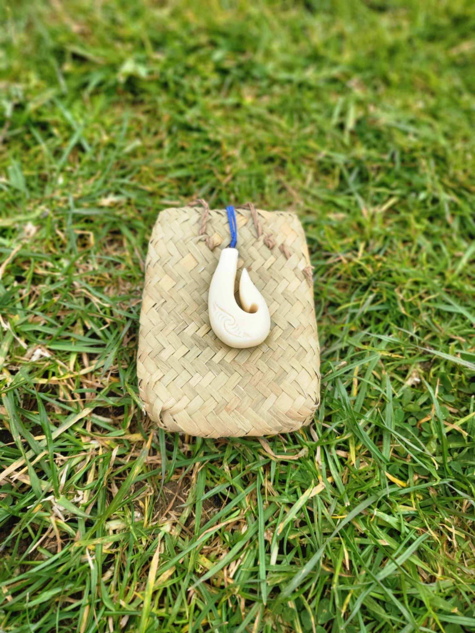 carved bone matau (hook) necklace with koru carvings on black cord
