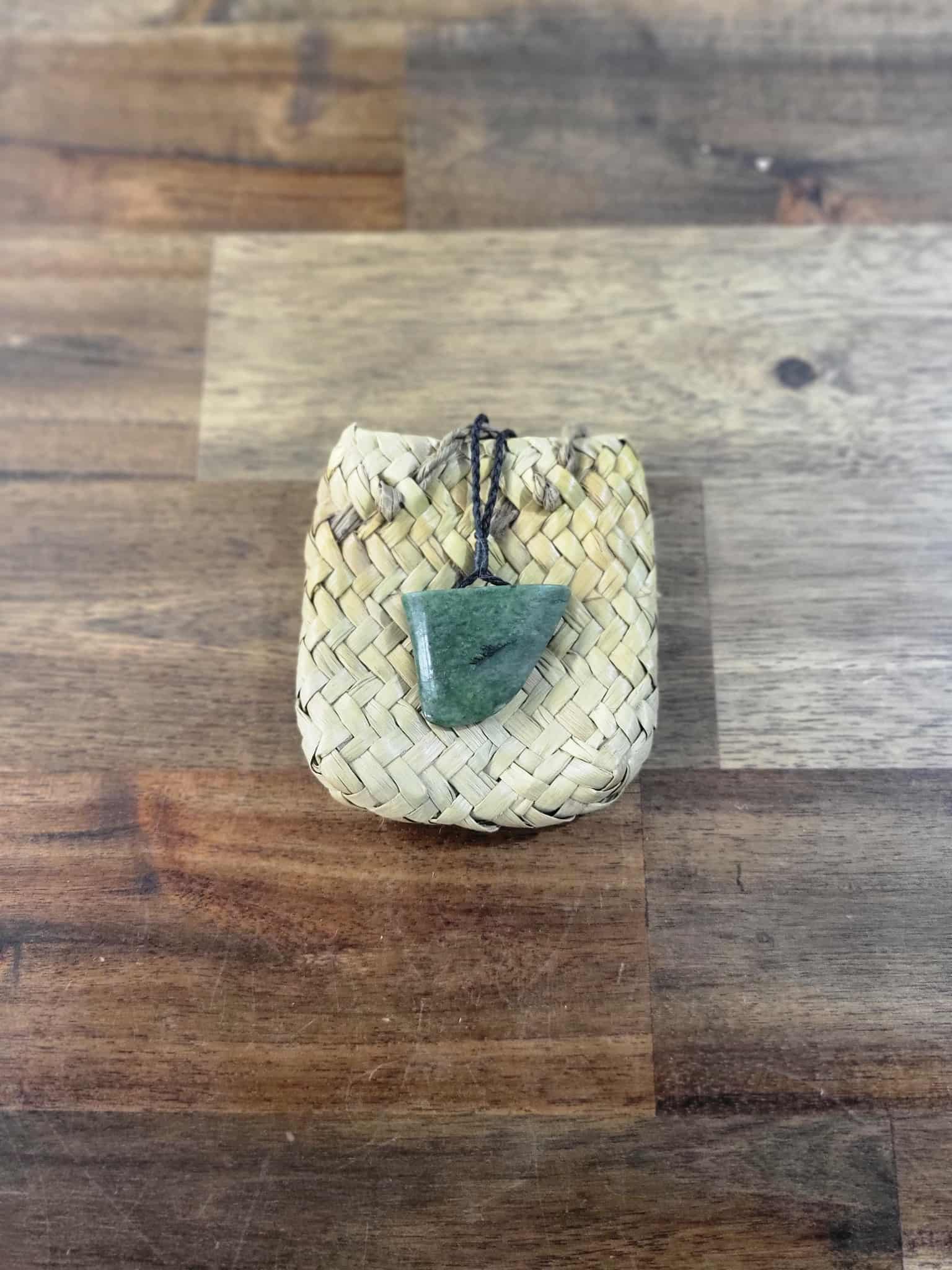 Carved pounamu (greenstone) niho (tooth) necklace on black braiding