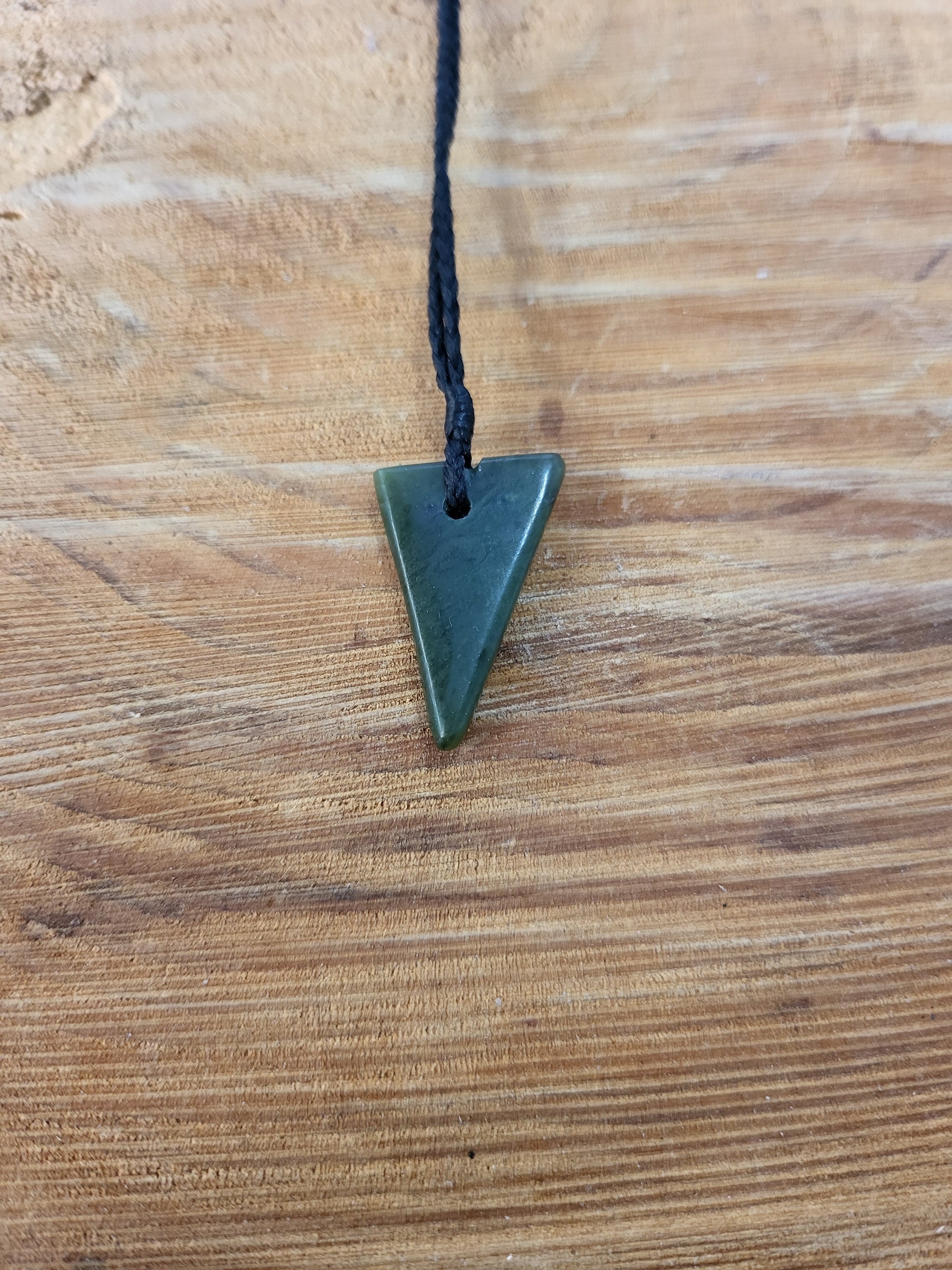 small carved pounamu niho (tooth) necklace on black cord