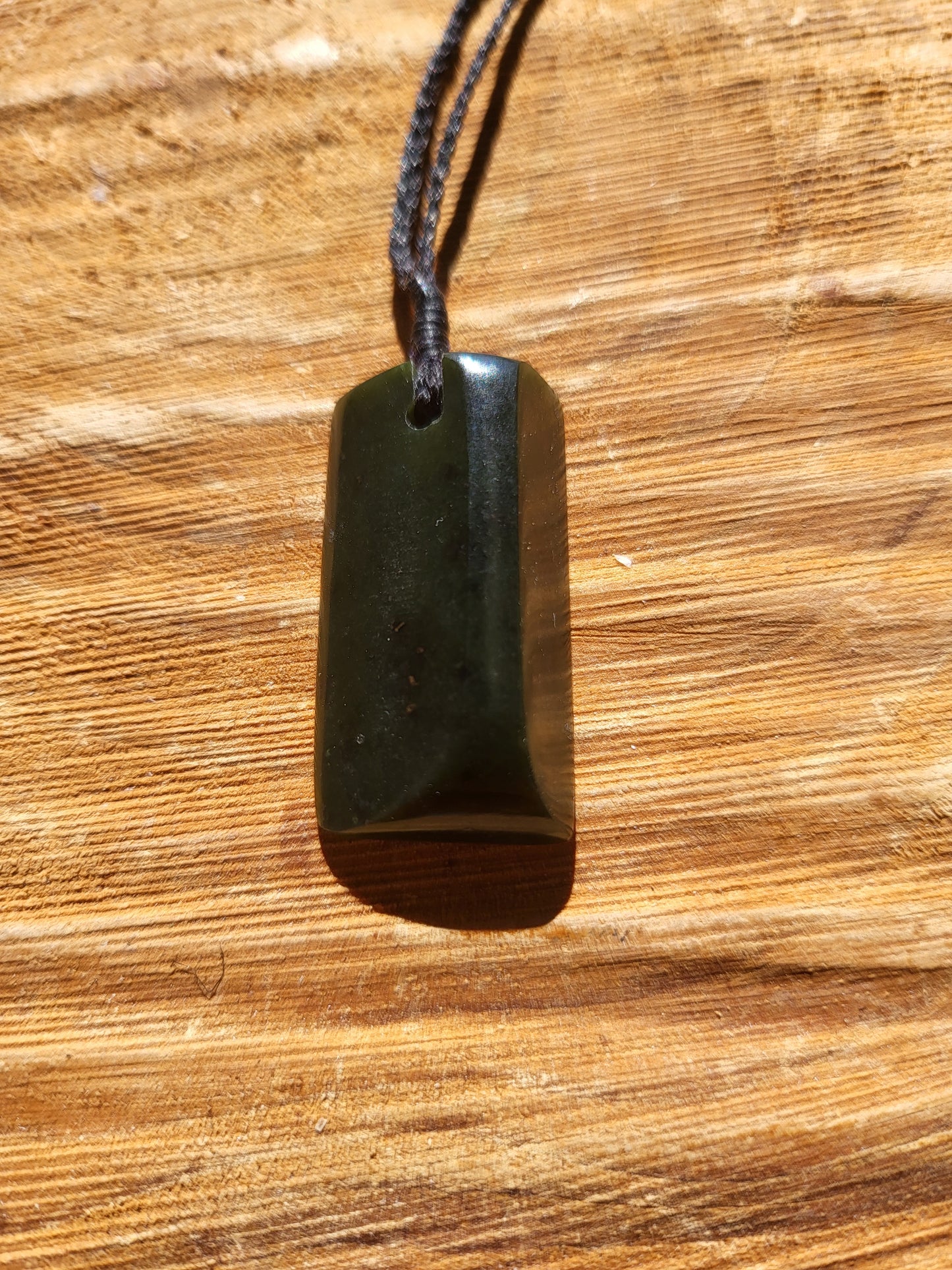 small carved pounamu toki (adze) necklace on black cord