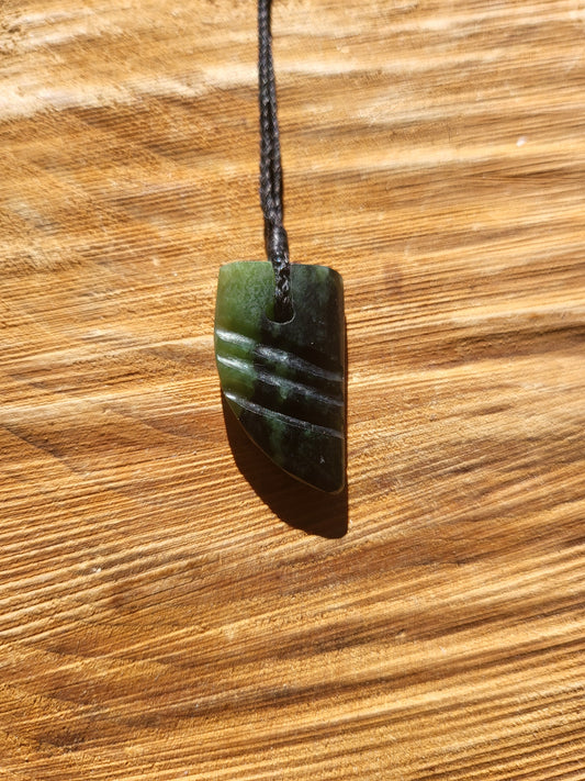small carved pounamu niho (tooth) necklace on black cord