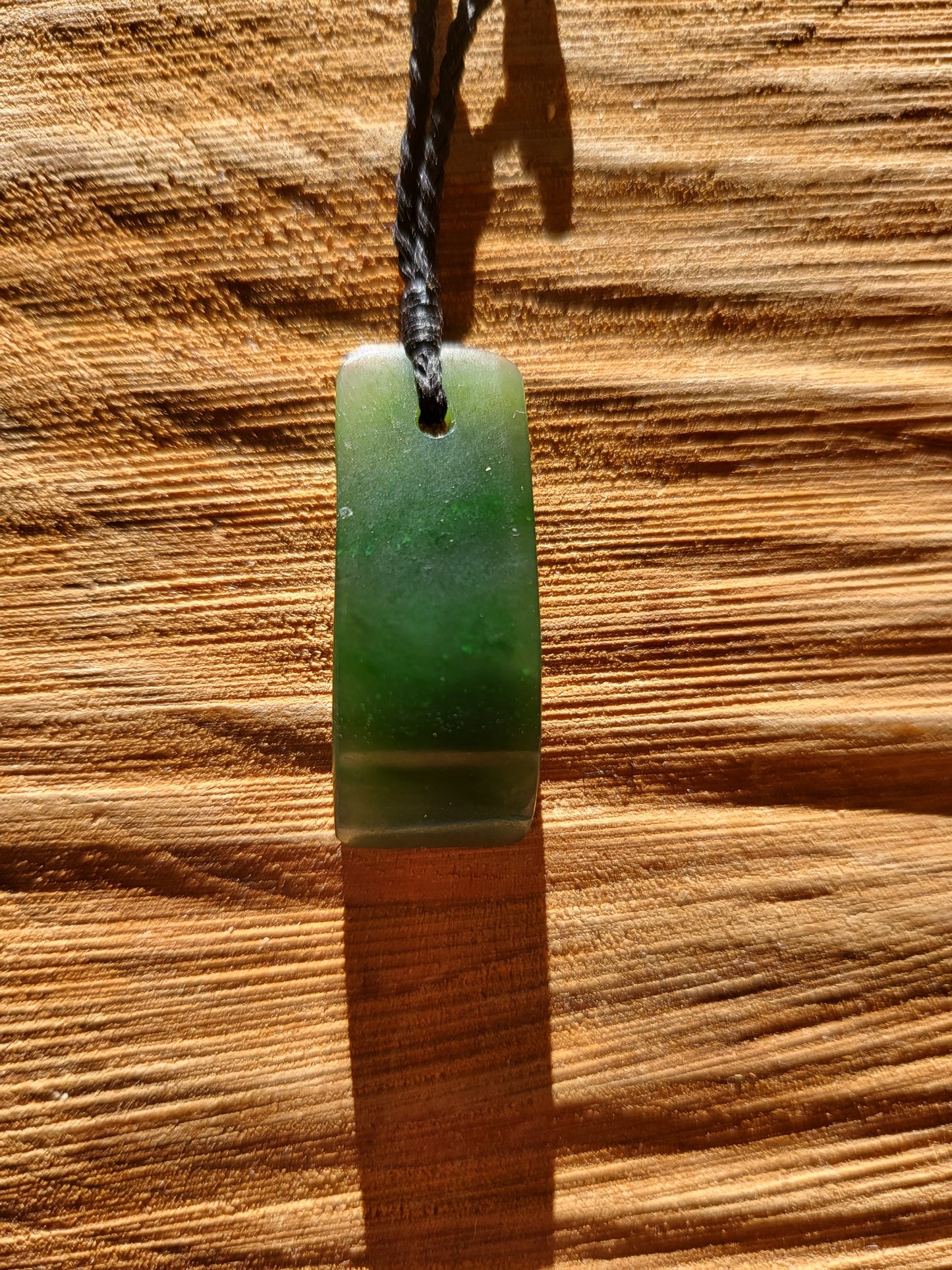 small carved pounamu toki (adze) necklace on black cord