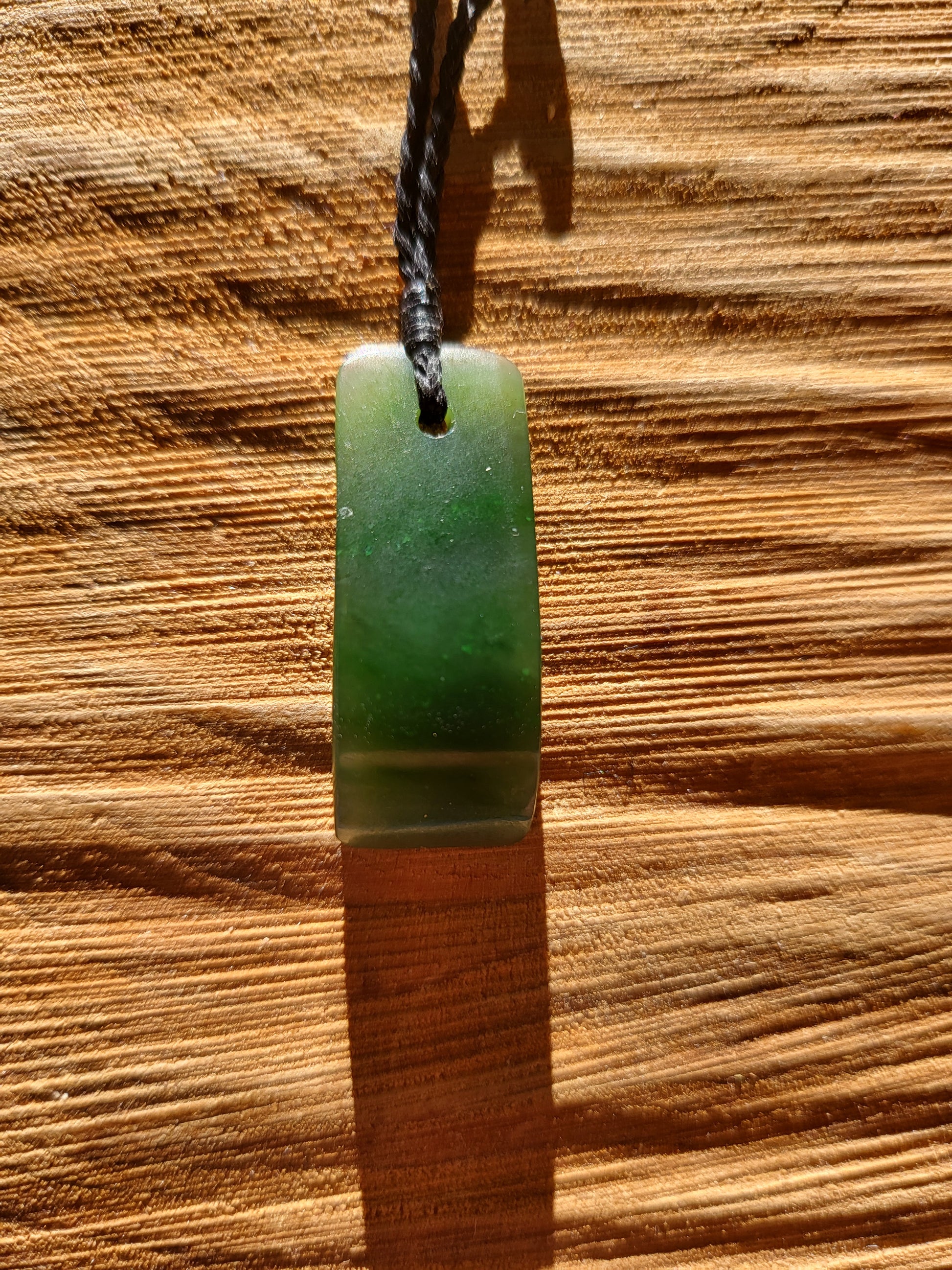 small carved pounamu toki (adze) necklace on black cord