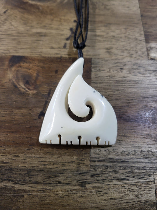carved bone matau (hook) with designs on black cord