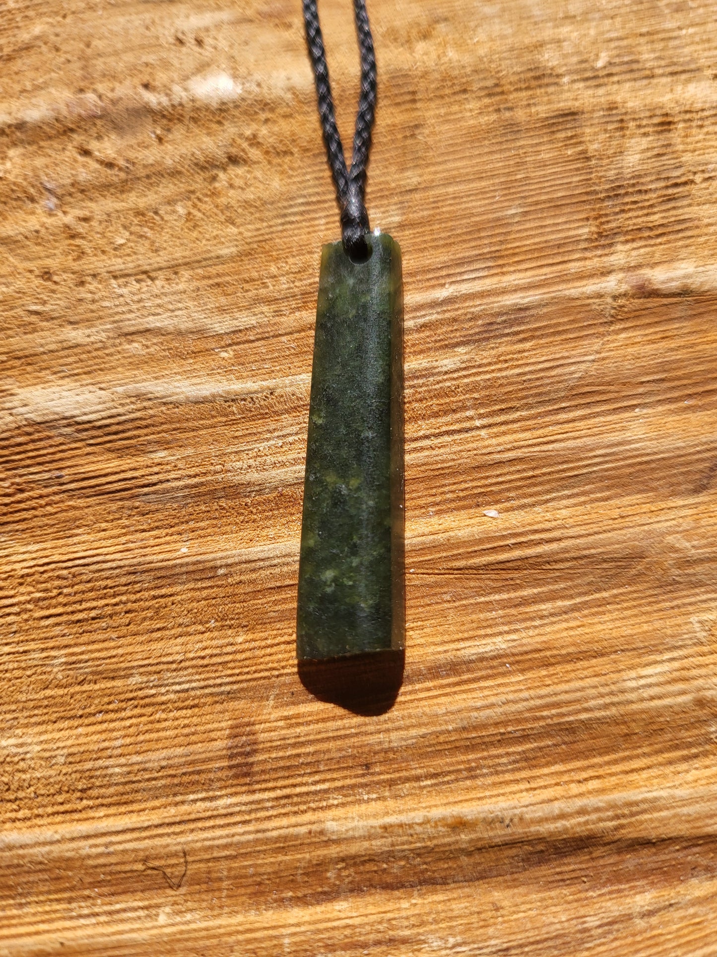 small carved pounamu toki (adze) necklace on black cord
