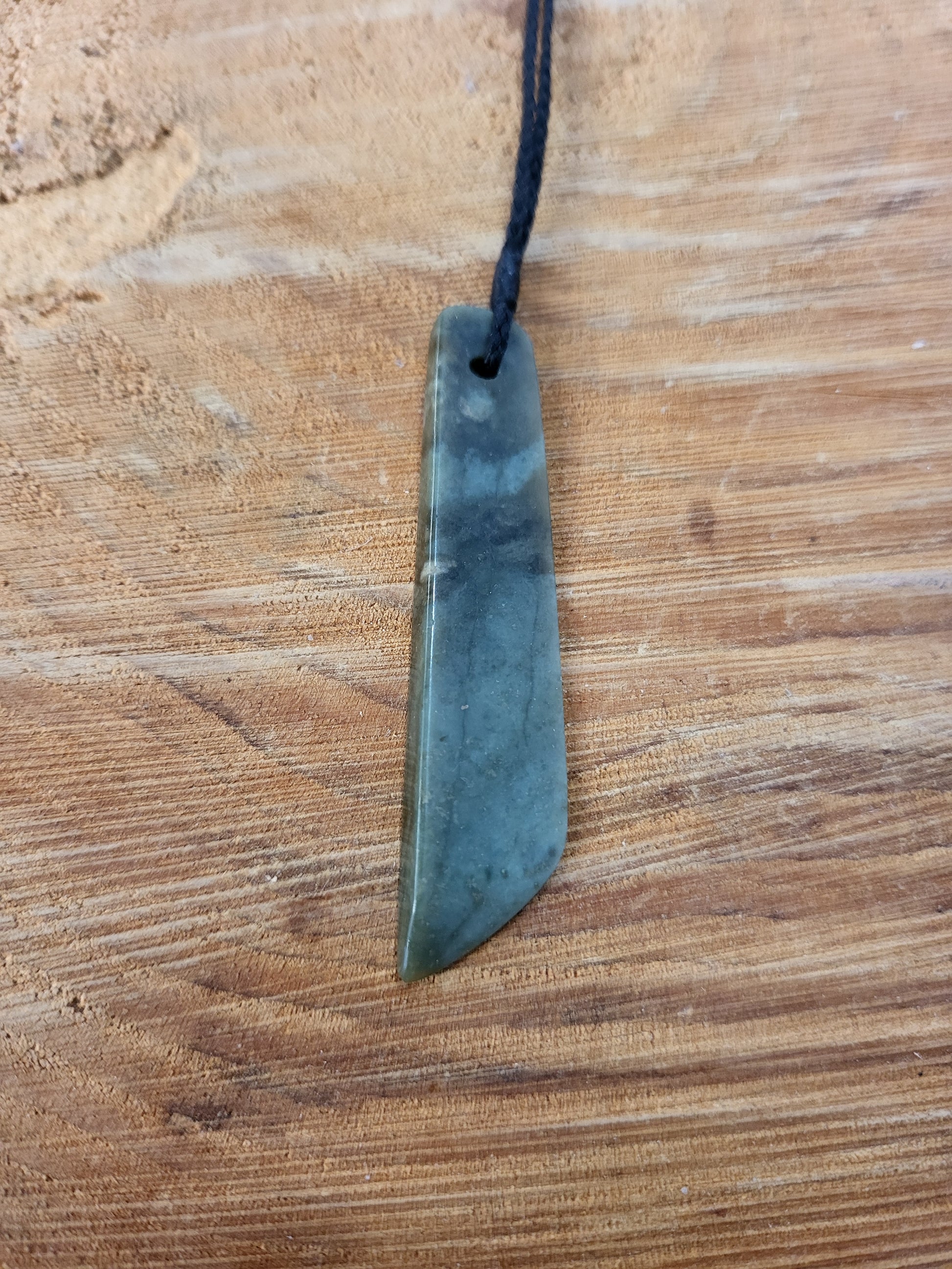 small carved pounamu toki (adze) necklace on black cord