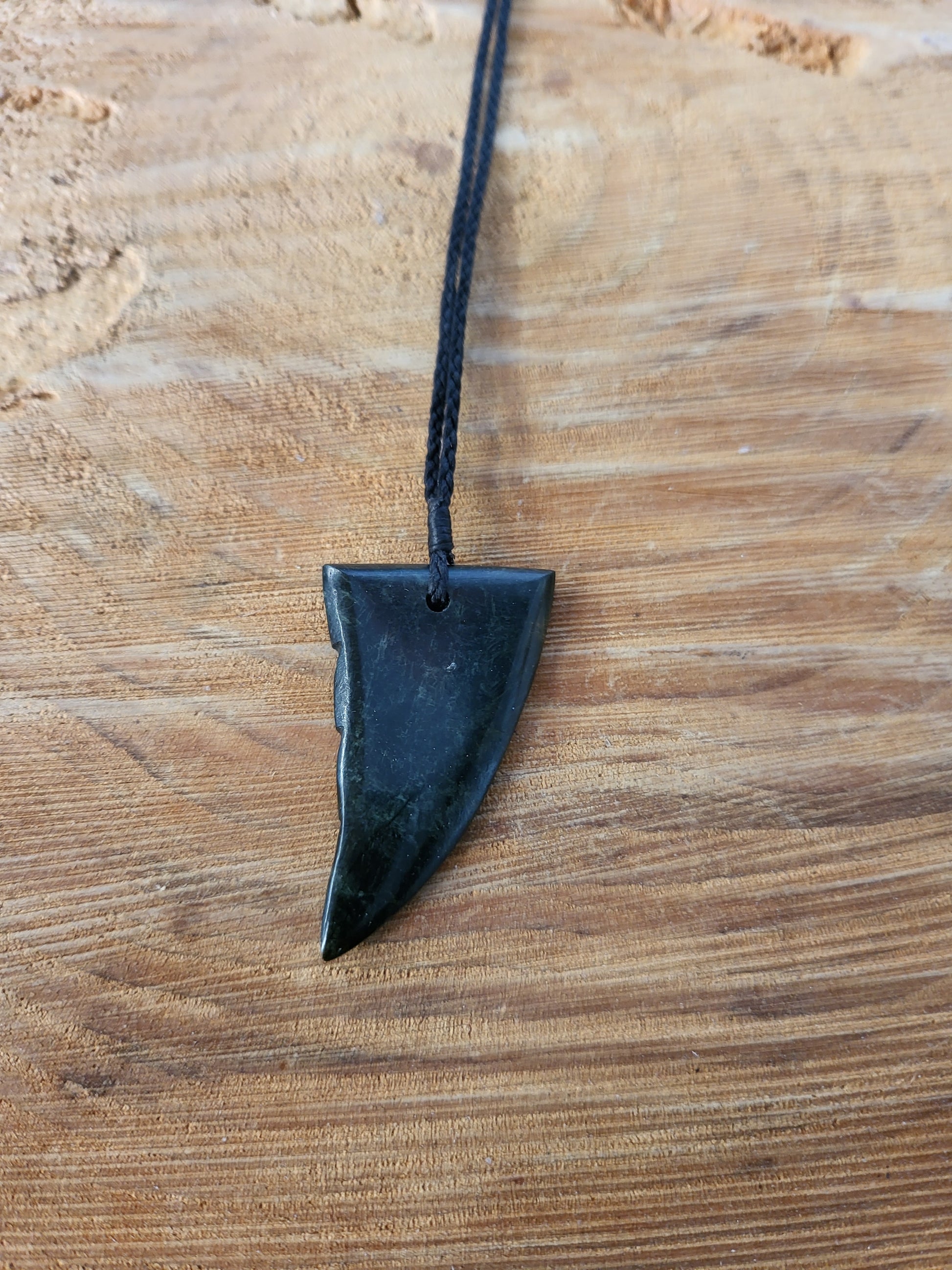small carved pounamu niho (tooth) necklace on black cord