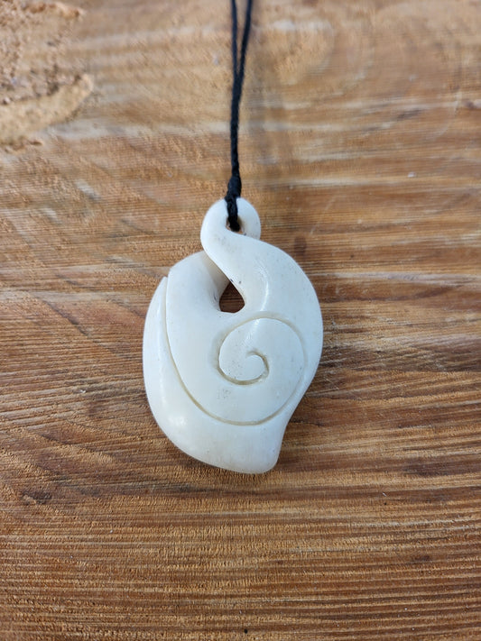 carved bone pikorua (double twist) necklace, decorated with koru (spiral) on black cord