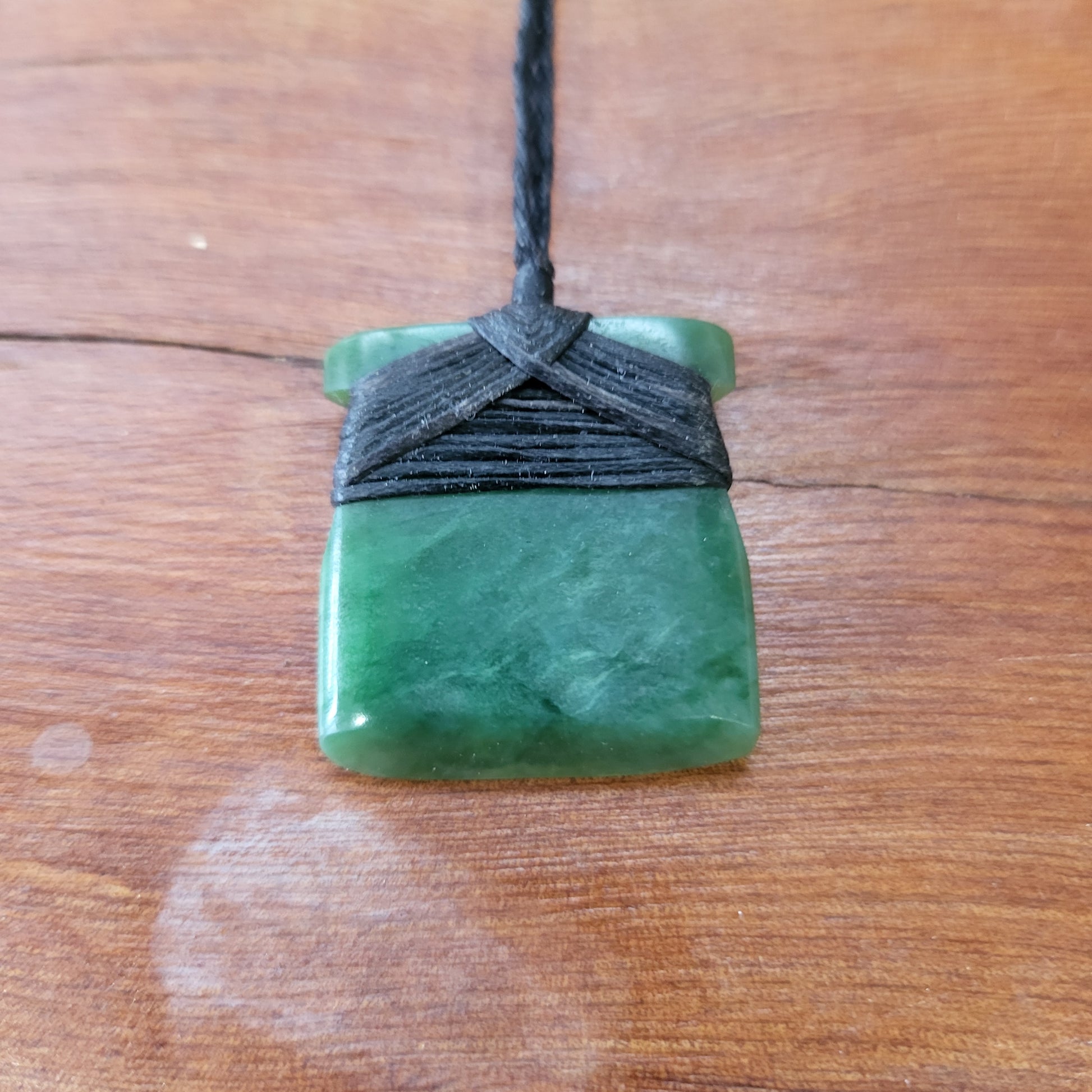 small carved pounamu toki (adze) necklace, on black cord