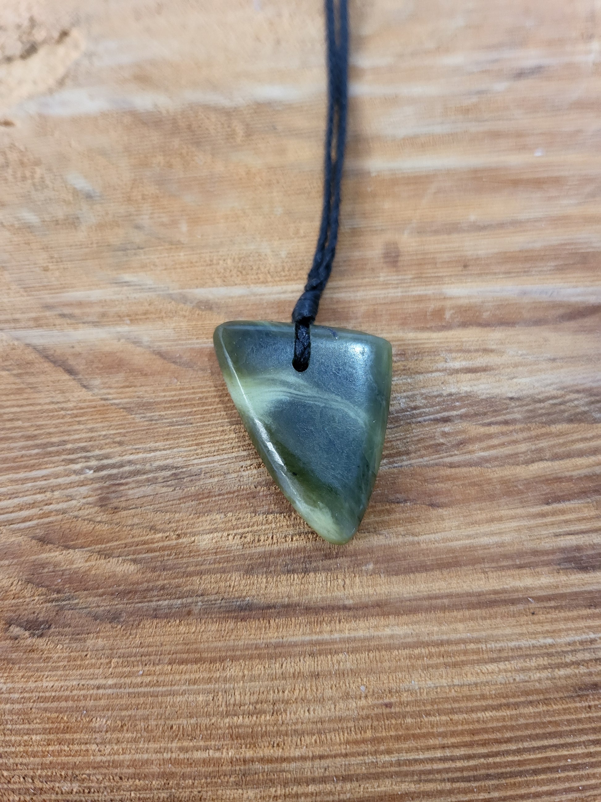 small carved pounamu niho (tooth) necklace on black cord