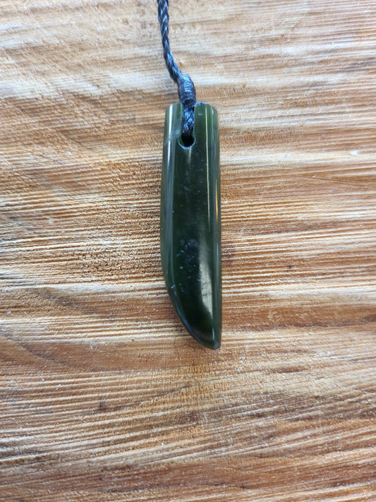small carved pounamu niho (tooth) necklace on black cord