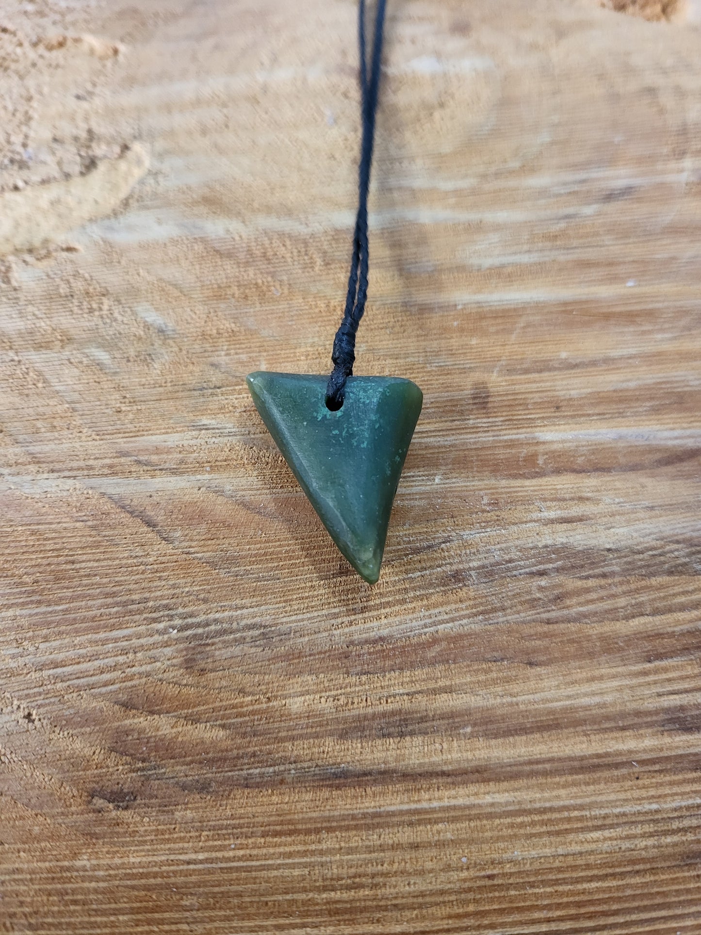 small carved pounamu niho (tooth) necklace on black cord