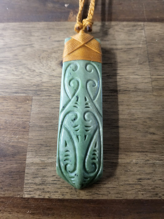 beautifully carved pounamu toki (adze) necklace, carved designs, light green, on tan cord